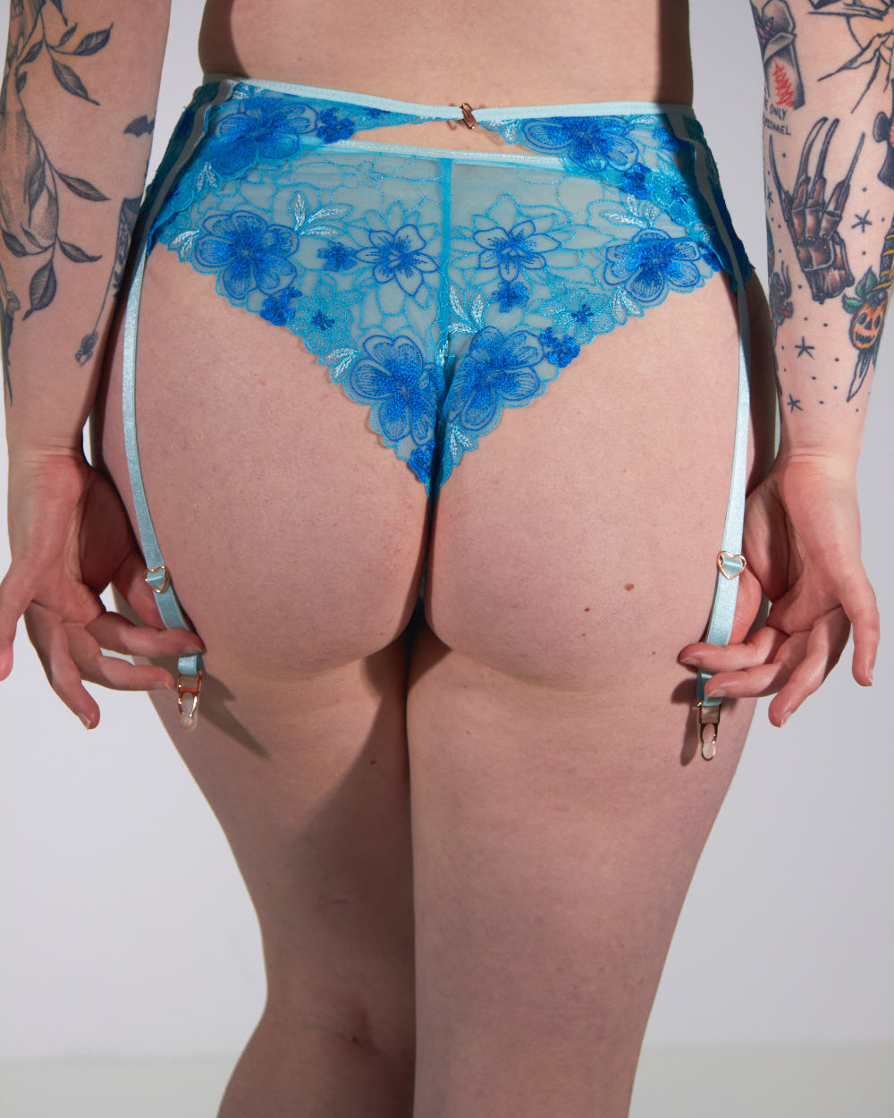 Person wearing blue floral lace underwear against a white background