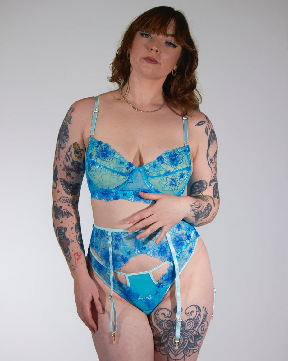 Woman wearing a blue patterned lingerie against a plain background