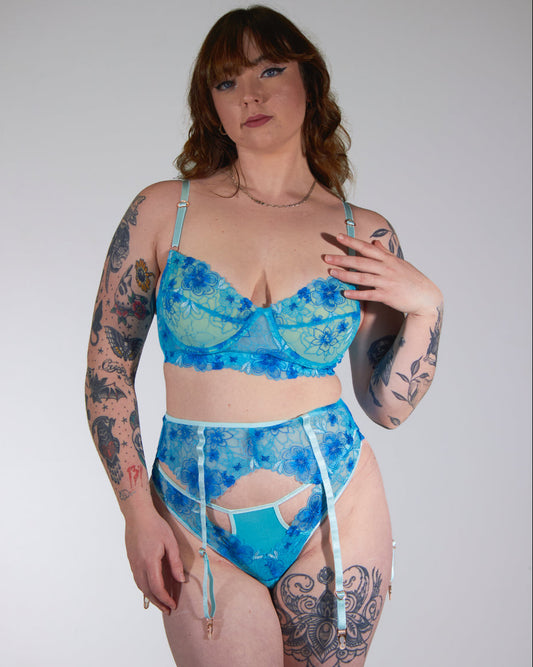 Woman wearing a blue floral lingerie set against a plain background