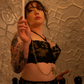 Person in lingerie holding a candle against a textured wall.