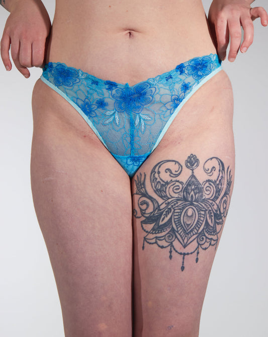 Person wearing blue lace underwear with a white background