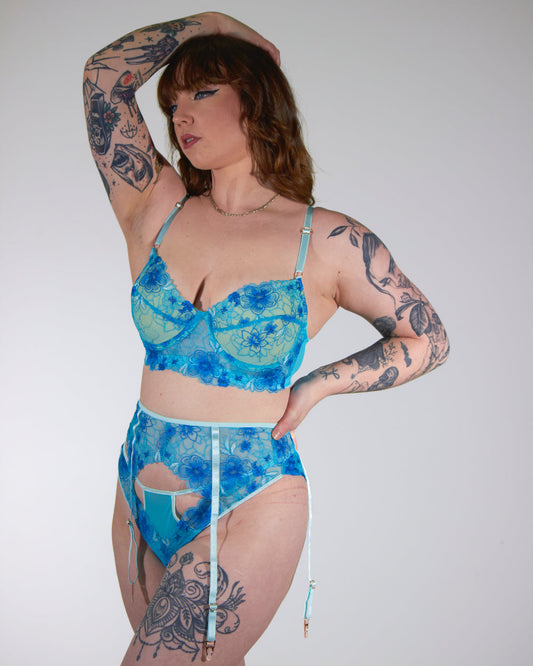 Person wearing a blue floral lingerie set against a plain background