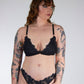 Woman wearing black lace lingerie against a plain background