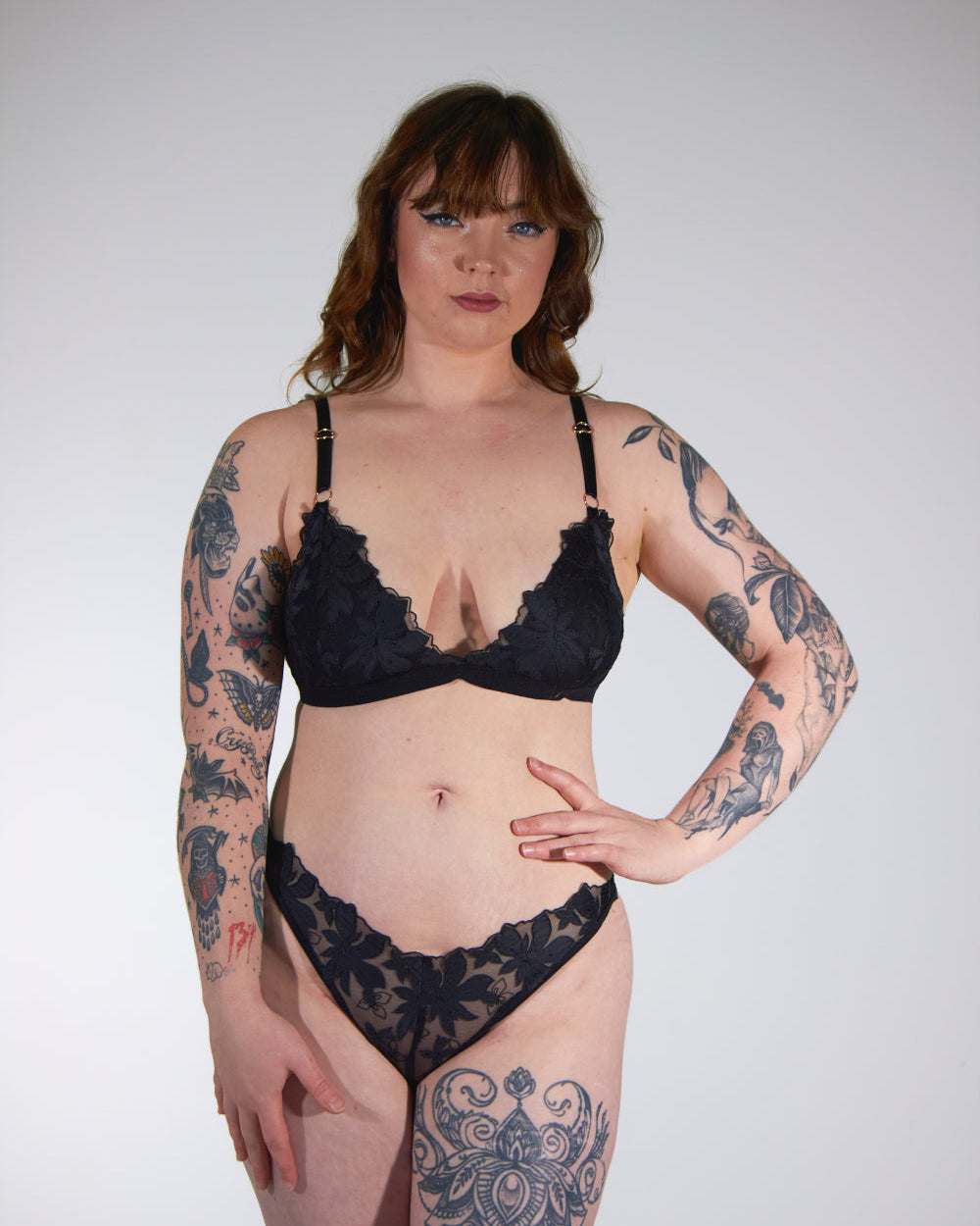 Woman wearing black lace lingerie against a plain background