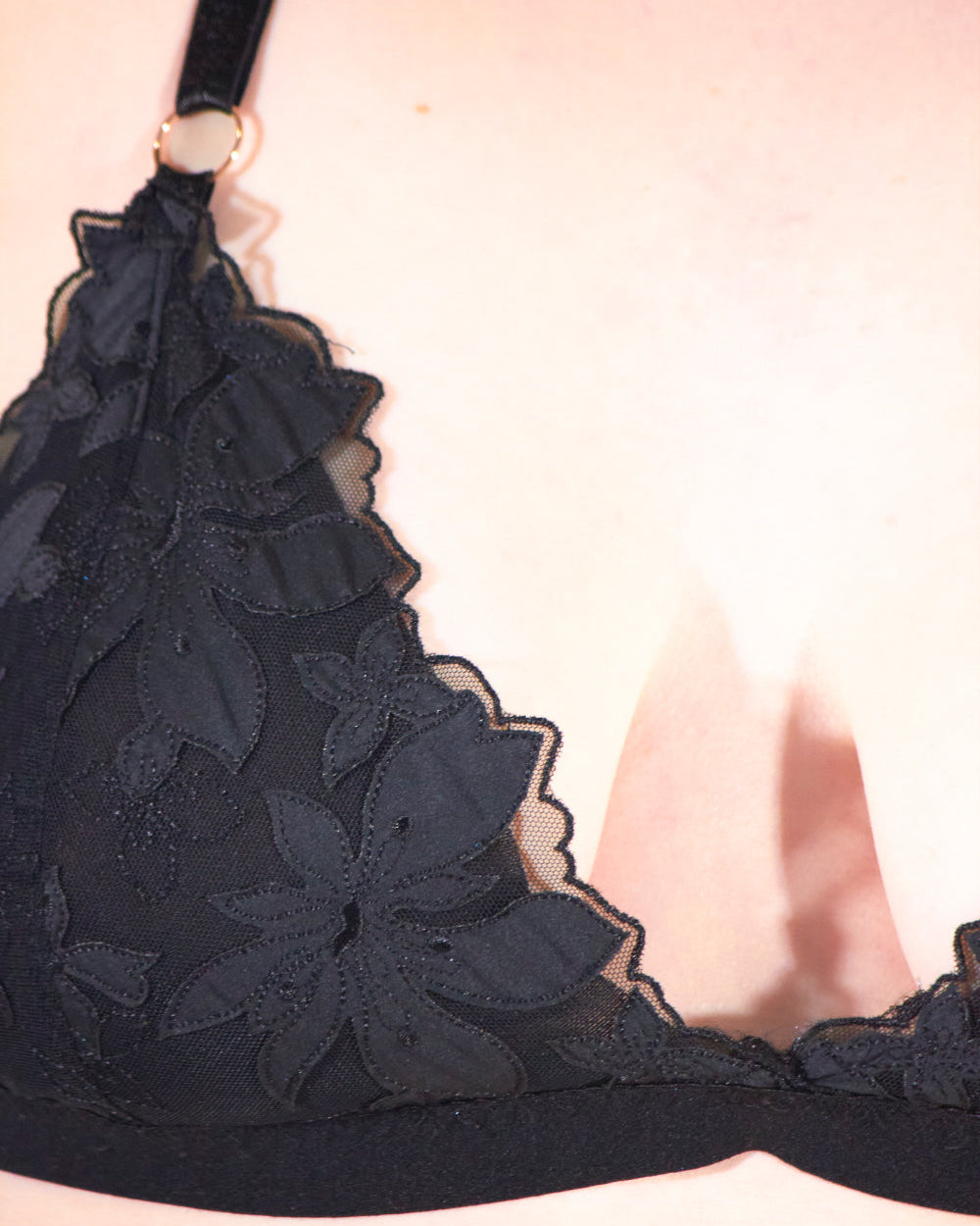 Black lace bra on a light pink background